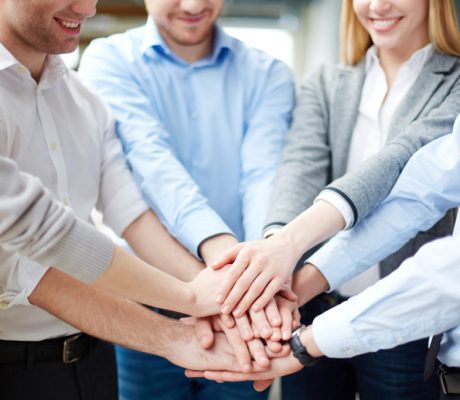 Arms of business partners keeping their hands on top of each other symbolizing teamwork